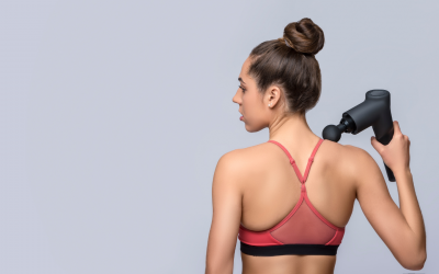 Image shows a woman massaging her shoulder with a massage gun